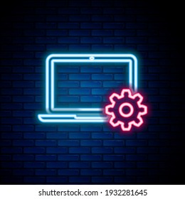Glowing neon line Laptop and gear icon isolated on brick wall background. Adjusting, service, setting, maintenance, repair, fixing. Colorful outline concept. Vector