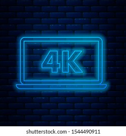 Glowing neon line Laptop screen with 4k video technology icon isolated on brick wall background.  Vector Illustration