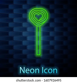 Glowing neon line Lollipop icon isolated on brick wall background. Candy sign. Food, delicious symbol. Valentines day. Love symbol.  Vector Illustration