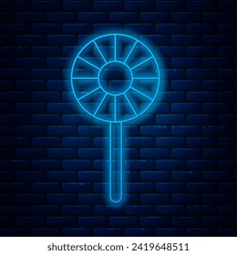 Glowing neon line Lollipop icon isolated on brick wall background. Candy sign. Food, delicious symbol.  Vector