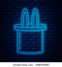 Glowing neon line Magician hat and rabbit ears icon isolated on brick wall background. Magic trick. Mystery entertainment concept.  Vector Illustration