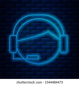 Glowing neon line Man with a headset icon isolated on brick wall background. Support operator in touch. Concept for call center, client support service.  Vector Illustration