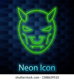 Glowing neon line Mask of the devil with horns icon isolated on brick wall background.  Vector Illustration