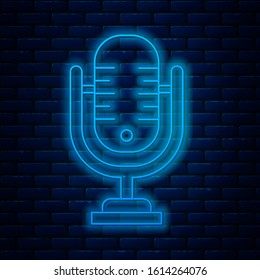 Glowing neon line Microphone icon isolated on brick wall background. On air radio mic microphone. Speaker sign.  Vector Illustration