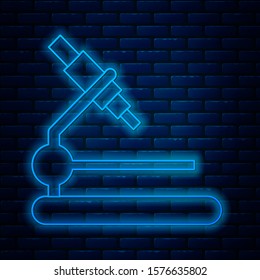 Glowing neon line Microscope icon isolated on brick wall background. Chemistry, pharmaceutical instrument, microbiology magnifying tool.  Vector Illustration