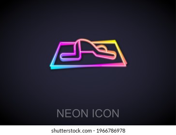 Glowing neon line Muslim man prays on the carpet icon isolated on black background.  Vector