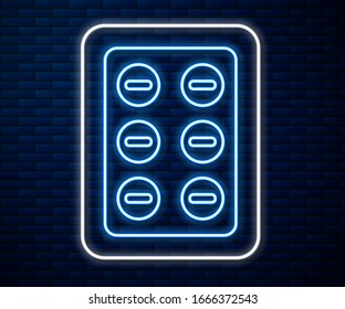 Glowing neon line Pills in blister pack icon isolated on brick wall background. Medical drug package for tablet, vitamin, antibiotic, aspirin.  Vector Illustration