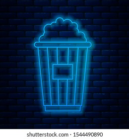Glowing neon line Popcorn in cardboard box icon isolated on brick wall background. Popcorn bucket box.  Vector Illustration