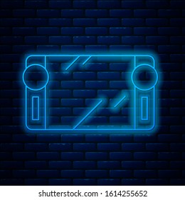 Glowing neon line Portable video game console icon isolated on brick wall background. Gamepad sign. Gaming concept.  Vector Illustration
