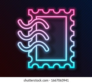Glowing neon line Postal stamp icon isolated on black background.  Vector Illustration