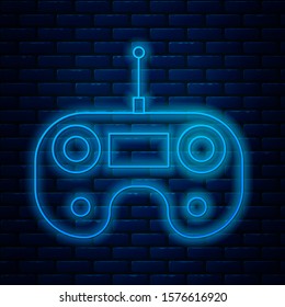 Glowing neon line Remote control icon isolated on brick wall background.  Vector Illustration