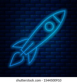 Glowing neon line Rocket ship with fire icon isolated on brick wall background. Space travel.  Vector Illustration