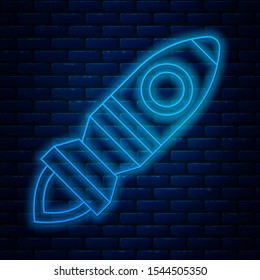 Glowing neon line Rocket ship with fire icon isolated on brick wall background. Space travel.  Vector Illustration