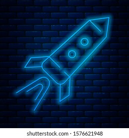 Glowing neon line Rocket ship with fire icon isolated on brick wall background. Space travel.  Vector Illustration