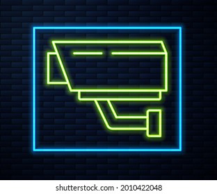 Glowing neon line Security camera icon isolated on brick wall background.  Vector