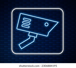 Glowing neon line Security camera icon isolated on brick wall background.  Vector