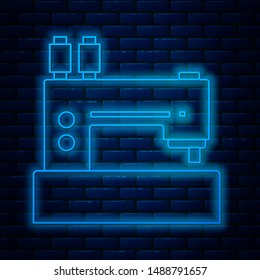 Glowing neon line Sewing machine icon isolated on brick wall background.  Vector Illustration