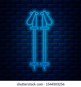 Glowing neon line Ski poles icon isolated on brick wall background. Extreme sport. Skiing equipment. Winter sports icon.  Vector Illustration