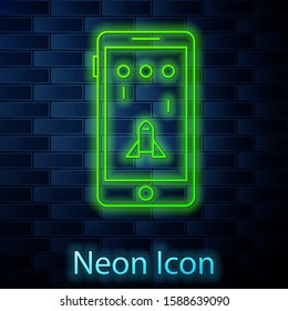 Glowing neon line Smartphone and playing in game icon isolated on brick wall background. Mobile gaming concept.  Vector Illustration