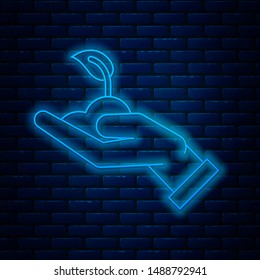 Glowing neon line Sprout in hand of environmental protection icon isolated on brick wall background. Seed and seedling. Planting sapling. Ecology concept.  Vector Illustration