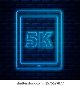 Glowing neon line Tablet with text 5k icon isolated on brick wall background.  Vector Illustration