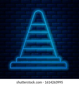 Glowing neon line Traffic cone icon isolated on brick wall background.  Vector Illustration