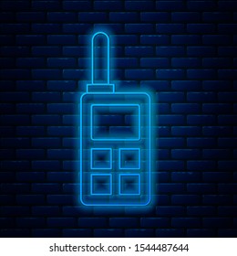 Glowing neon line Walkie talkie icon isolated on brick wall background. Portable radio transmitter icon. Radio transceiver sign.  Vector Illustration