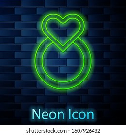 Glowing neon line Wedding rings icon isolated on brick wall background. Bride and groom jewelry sign. Marriage symbol. Diamond ring.  Vector Illustration