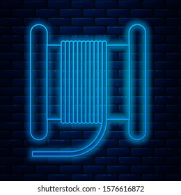 Glowing neon line Wire electric cable on a reel or drum icon isolated on brick wall background.  Vector Illustration