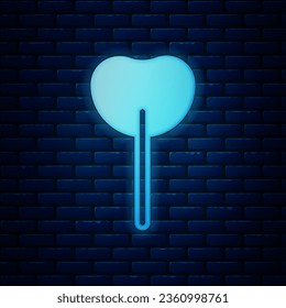 Glowing neon Lollipop icon isolated on brick wall background. Food, delicious symbol.  Vector