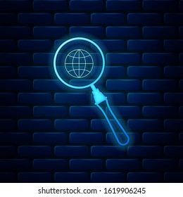 Glowing neon Magnifying glass with globe icon isolated on brick wall background. Analyzing the world. Global search sign.  Vector Illustration