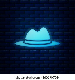 Glowing neon Man hat with ribbon icon isolated on brick wall background.  Vector Illustration
