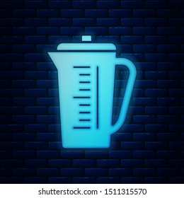 Glowing neon Measuring cup to measure dry and liquid food icon isolated on brick wall background. Plastic graduated beaker with handle.  Vector Illustration