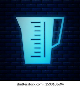 Glowing neon Measuring cup to measure dry and liquid food icon isolated on brick wall background. Plastic graduated beaker with handle.  Vector Illustration