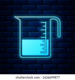 Glowing neon Measuring cup to measure dry and liquid food icon isolated on brick wall background. Plastic graduated beaker with handle.  Vector Illustration