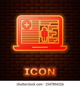 Glowing neon Medical clinical record on laptop icon isolated on brick wall background. Health insurance form. Prescription, medical check marks report.  Vector Illustration