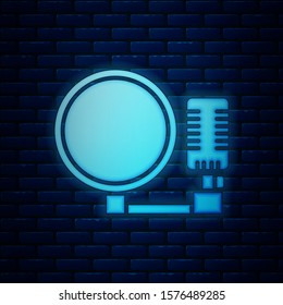 Glowing neon Microphone icon isolated on brick wall background. On air radio mic microphone. Speaker sign.  Vector Illustration