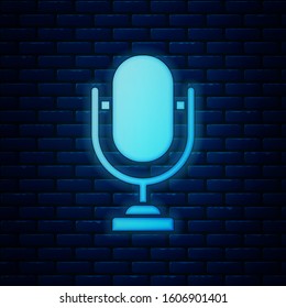 Glowing neon Microphone icon isolated on brick wall background. On air radio mic microphone. Speaker sign.  Vector Illustration