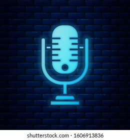Glowing neon Microphone icon isolated on brick wall background. On air radio mic microphone. Speaker sign.  Vector Illustration
