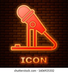 Glowing neon Microphone icon isolated on brick wall background. On air radio mic microphone. Speaker sign.  Vector Illustration
