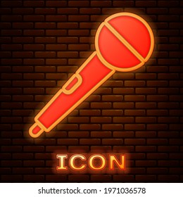 Glowing neon Microphone icon isolated on brick wall background. On air radio mic microphone. Speaker sign.  Vector