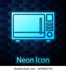 Glowing neon Microwave oven icon isolated on brick wall background. Home appliances icon. Vector Illustration