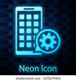Glowing neon Mobile Apps and gear icon isolated on brick wall background. Adjusting app, service concept, setting options, maintenance, repair, fixing. Vector Illustration