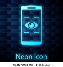 Glowing neon Mobile phone and eye scan icon isolated on brick wall background. Scanning eye. Security check symbol. Cyber eye sign. Vector Illustration
