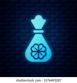 Glowing neon Money bag with four leaf clover icon isolated on brick wall background. Cash Banking currency sign. Happy Saint Patricks day.  Vector Illustration