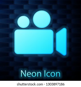Glowing neon Movie or Video camera icon isolated on brick wall background. Cinema camera icon. Vector Illustration