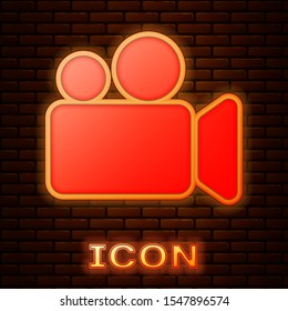Glowing neon Movie or Video camera icon isolated on brick wall background. Cinema camera icon.  Vector Illustration