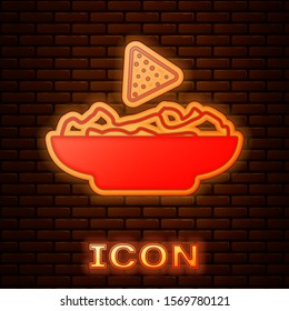 Glowing neon Nachos in plate icon isolated on brick wall background. Tortilla chips or nachos tortillas. Traditional mexican fast food.  Vector Illustration