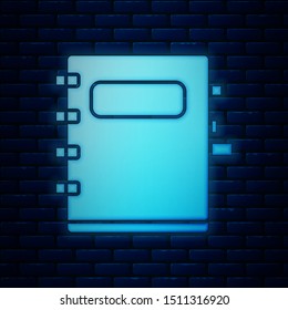 Glowing neon Notebook icon isolated on brick wall background. Spiral notepad icon. School notebook. Writing pad. Diary for school.  Vector Illustration