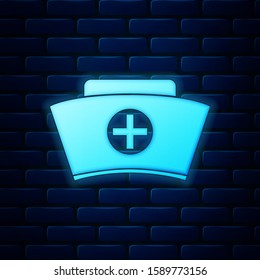 Glowing neon Nurse hat with cross icon isolated on brick wall background. Medical nurse cap sign.  Vector Illustration